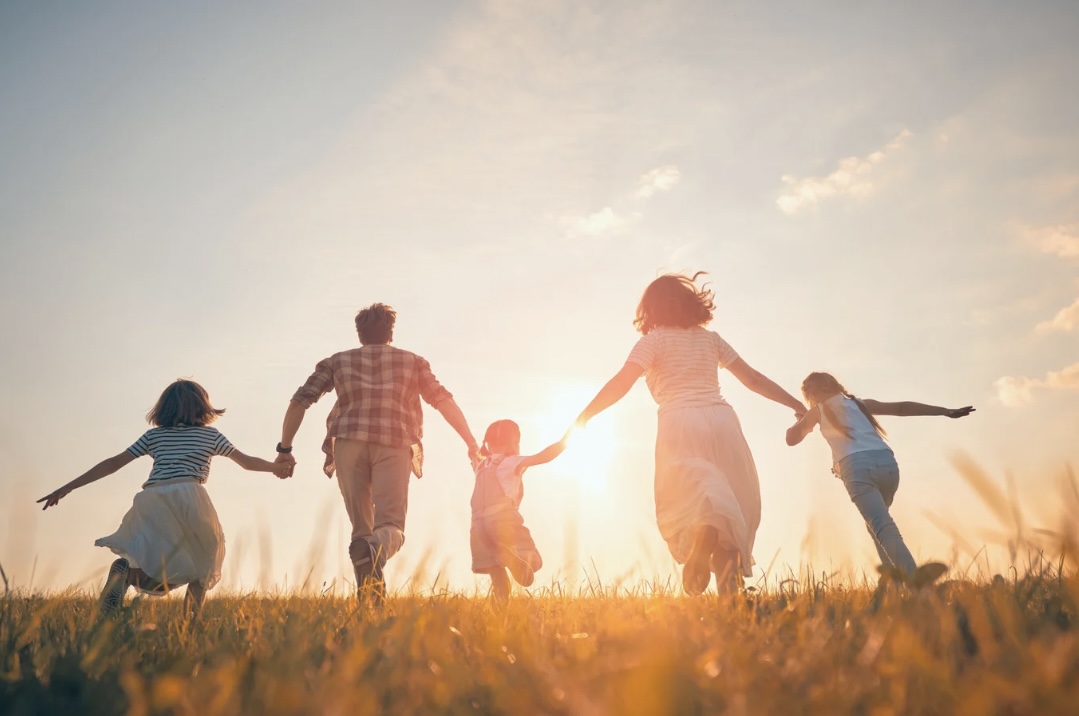 Familie mit drei Kindern im Sonnenuntergang auf einem Feld