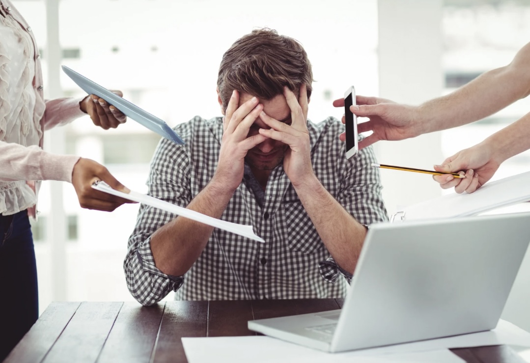 ein gestresster Mann auf der Arbeit, der viele Aufgaben gestellt bekommt